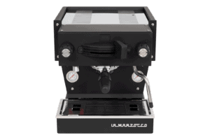 Badger and Dodo Coffee Roasters: The stylish La Marzocco Linea Mini - Nera espresso machine features dual pressure gauges, a group head, and a frothing wand. Its black and silver design with La Marzocco on the drip tray adds elegance against a plain gray background.