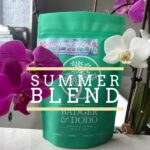 Summer Blend” coffee from Badger & Dodo sits centered among blooming orchids, with large white overlay text reading “SUMMER BLEND.” The bag features tropical floral artwork and is photographed indoors on a light surface near a window.