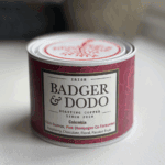 A cylindrical tin of Badger & Dodo coffee with a deep magenta label. The label reads "Irish Badger & Dodo Roasting Coffee Since 2008" and describes the contents as "Colombia – Elkin Guzman, Pink Champagne Co-Fermented" with flavor notes of raspberry, chocolate, floral, and passion fruit. The tin features a decorative lid with a red tree design.