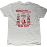 The image shows the back of a white T-shirt with a large red and black graphic for the Irish Aeropress Championships. The top text reads “IRISH Aeropress Championships” in bold red letters. Below that, it says “Presented by Badger & Dodo Boutique Coffee Roasters” in black text. The design features two stylized Aeropress coffee makers placed on brick-like bases, one on each side of a central sailing ship graphic. At the bottom, large red text reads “CORK 2025.”