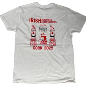 The image shows the back of a white T-shirt with a large red and black graphic for the Irish Aeropress Championships. The top text reads “IRISH Aeropress Championships” in bold red letters. Below that, it says “Presented by Badger & Dodo Boutique Coffee Roasters” in black text. The design features two stylized Aeropress coffee makers placed on brick-like bases, one on each side of a central sailing ship graphic. At the bottom, large red text reads “CORK 2025.”