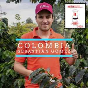 A man wearing a red polo shirt and a red "Cofinet" cap stands among coffee plants, giving a thumbs up. Overlaid text reads "Colombia Sebastián Gómez." In the top right corner, there is a stamp-like logo for the "Irish Aeropress Championships 2025" featuring an illustration of an Aeropress coffee maker.